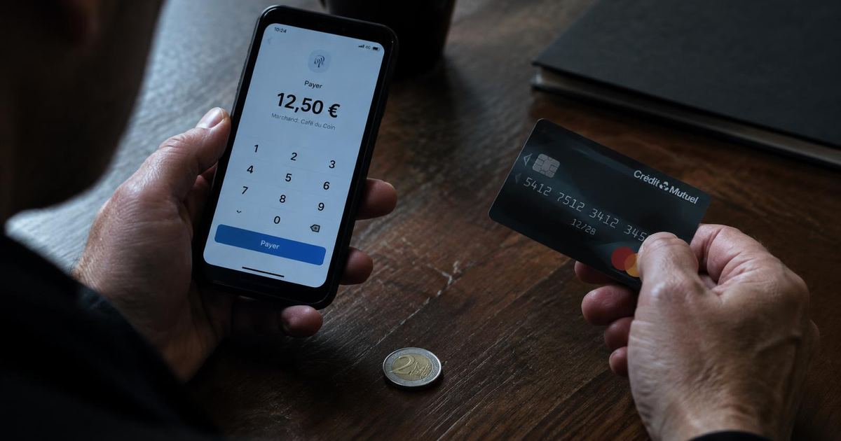 Hands holding a phone payment screen and a bank card beside a 2 euro coin